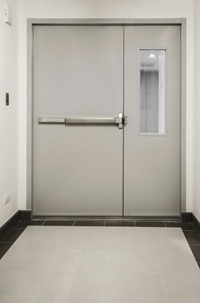 photo of gray steel door in white hallway, with sidelight with single pane