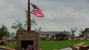photo of standing American flag in front of building destroyed by tornado